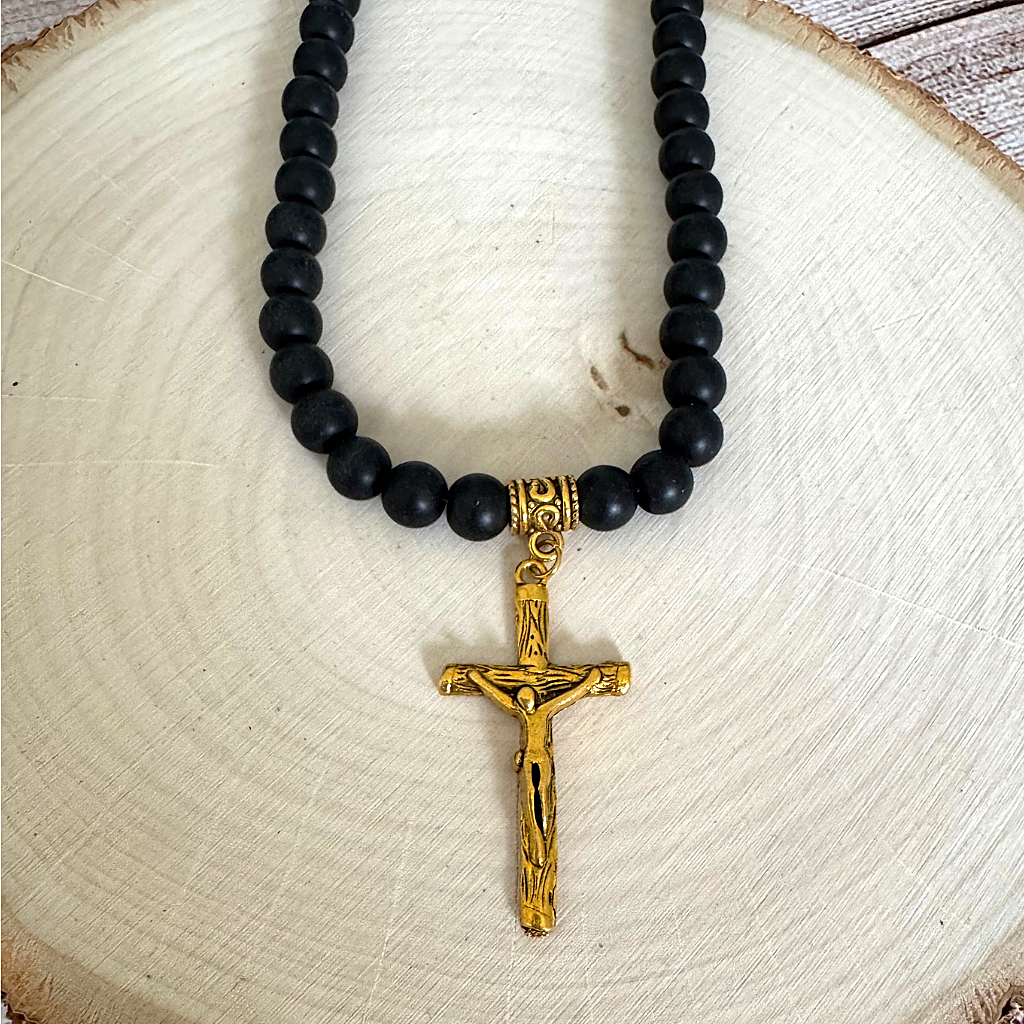 Matte Black Onyx and Gold Cross with Jesus Mens Beaded Necklace On Light Wood