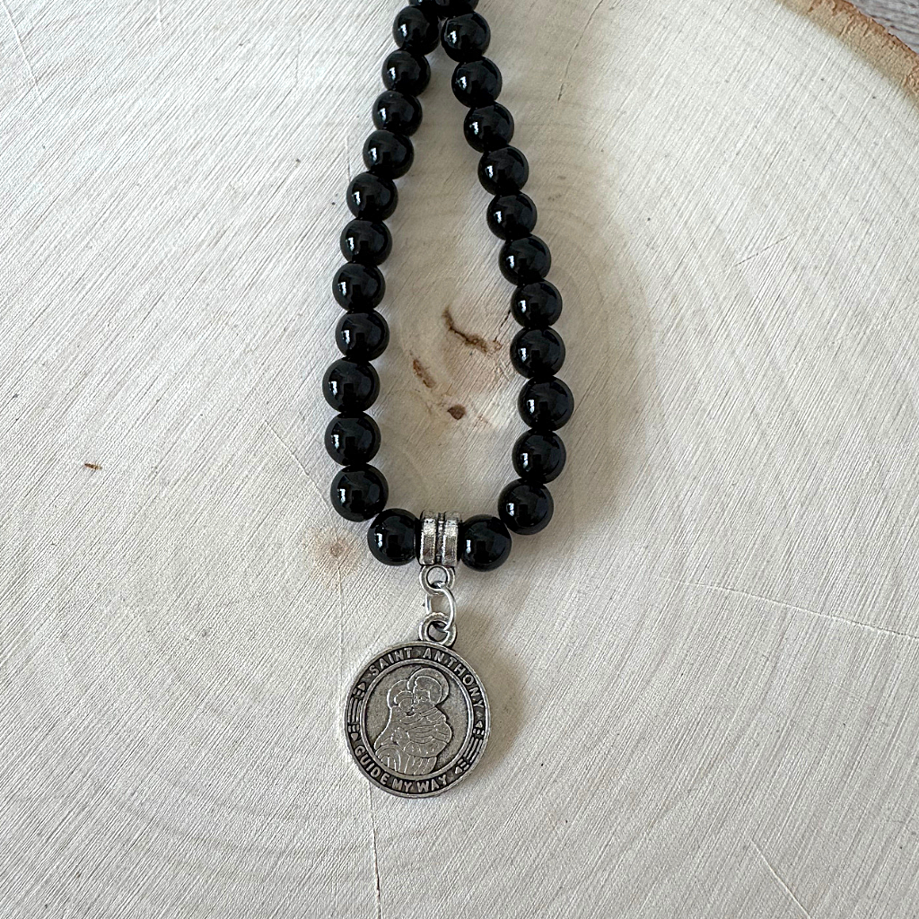 Mens Black Onyx 6mm St. Anthony Pendant Beaded Necklace On A Light Wood Table