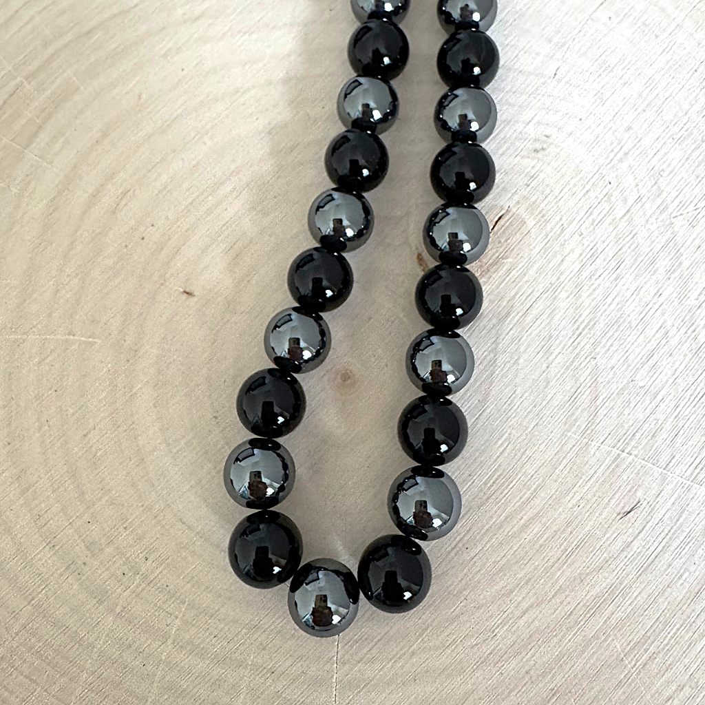 Mens Black Onyx and Hematite 10mm Beaded Necklace On Light Wood Table