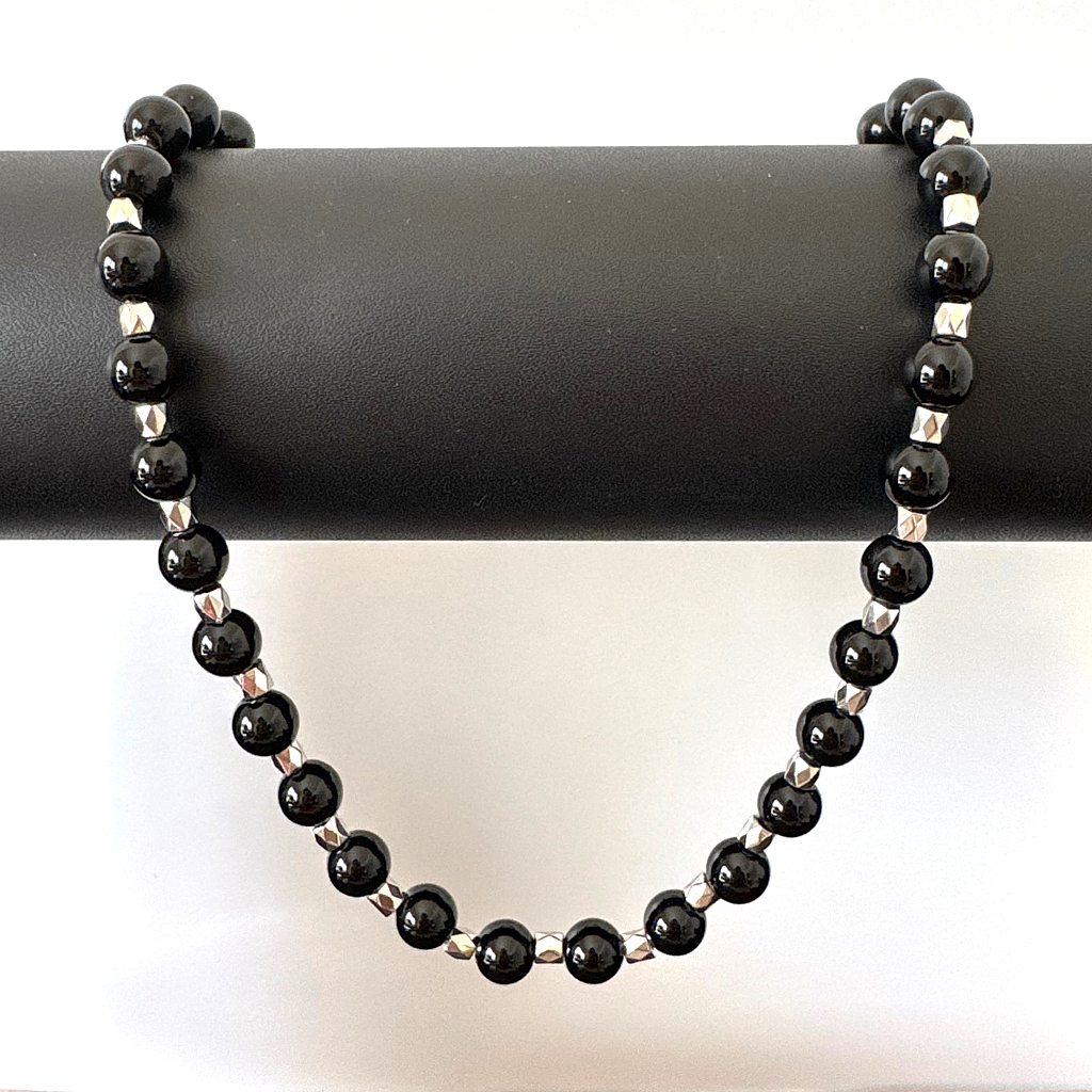 Mens Black Onyx and Silver Hexagon Beaded Necklaceon a black cylindrical stand with a white background