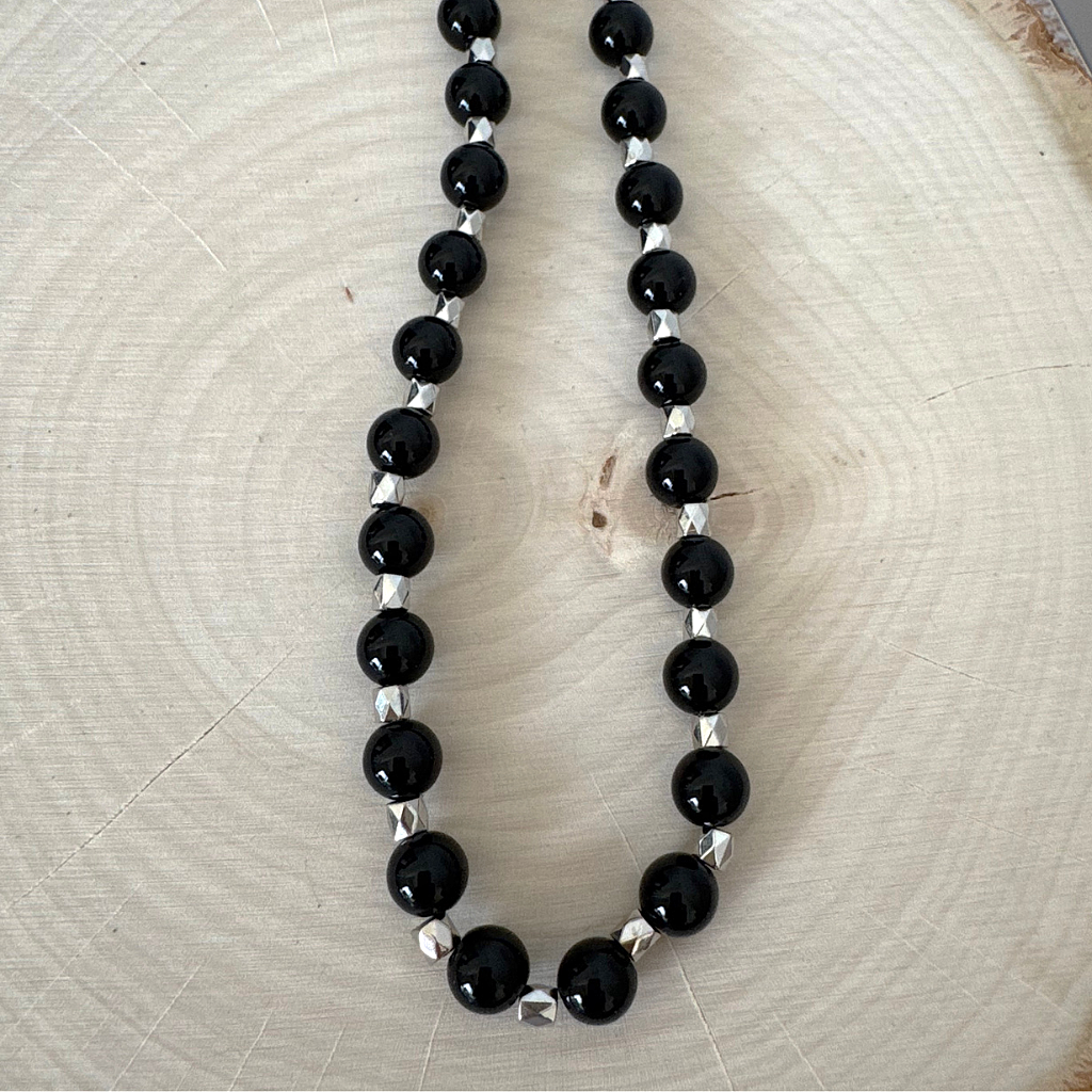 Mens Black Onyx and Silver Hexagon Beaded Necklace on a light wooden surface