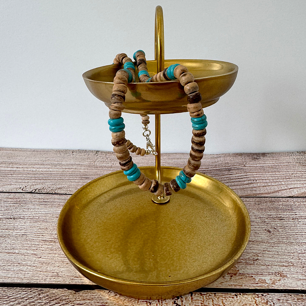Gold jewelry stand with Mens Brown Coconut Shell and Magnesite Heishi Beaded Necklace on a wooden surface.