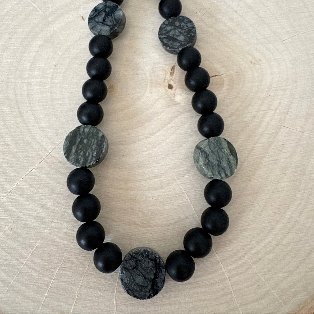Mens Matte Black Onyx and Picasso Serpentine Beaded Necklace On Wood Table.