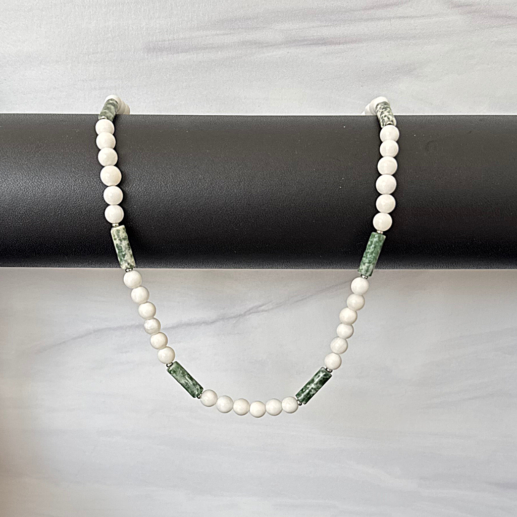 Mens White Shell and Green Jasper Beaded Necklace Draped On a Black Bar