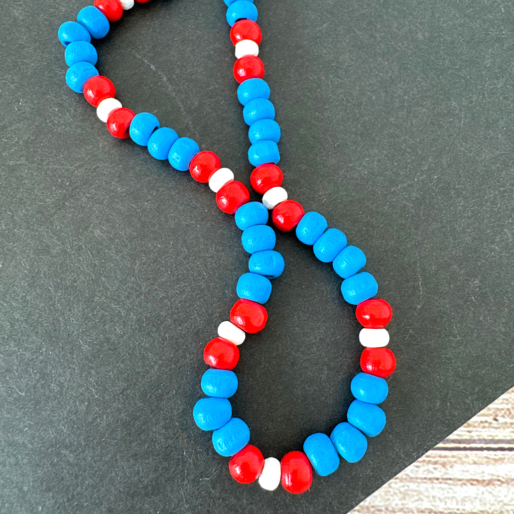 Red White and Blue Wood Beaded Mens Necklace on a dark surface