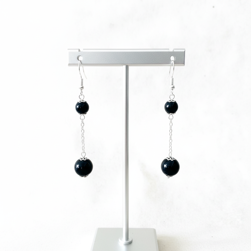 Black Onyx Double Bead Long Earrings on display stand.