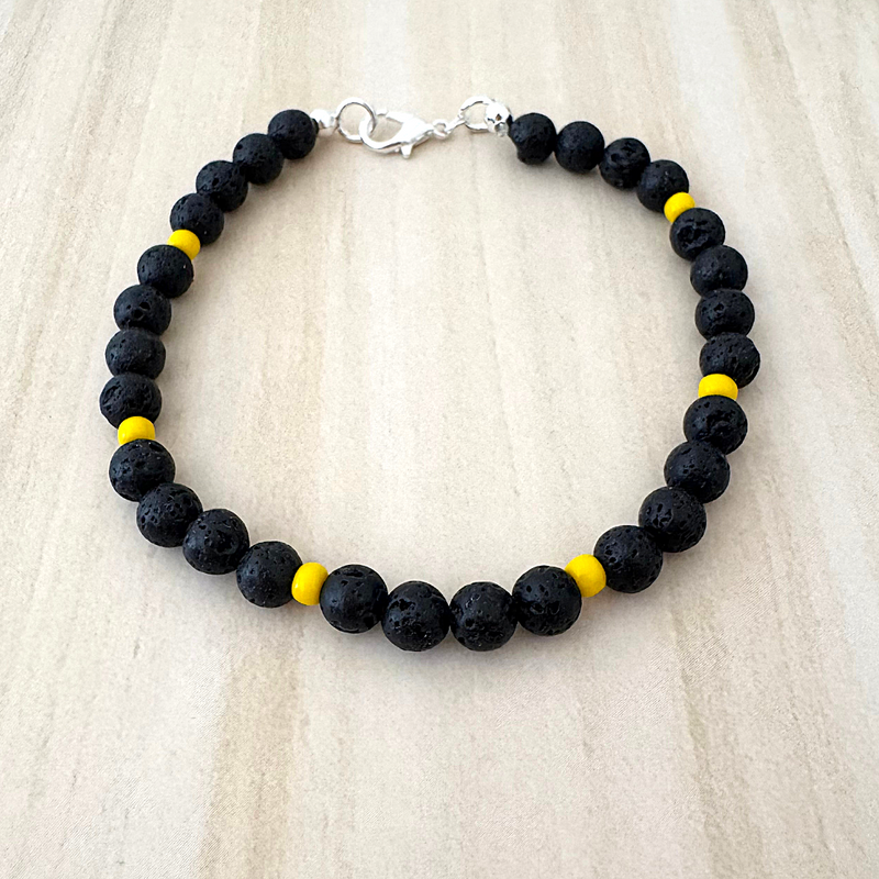 A beaded bracelet with black lava beads and yellow Toho beads.