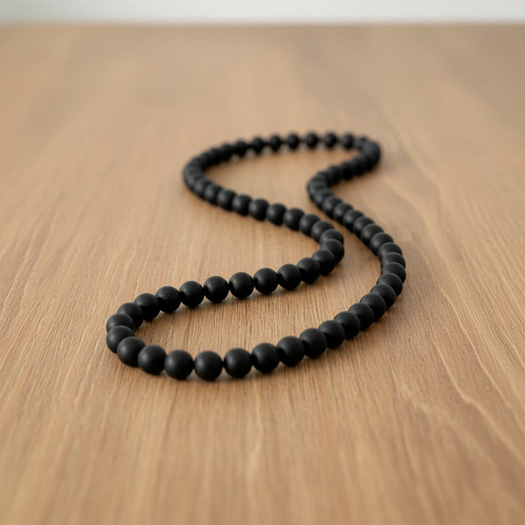Men's Black Onyx Matte Beaded Necklace on light brown table.