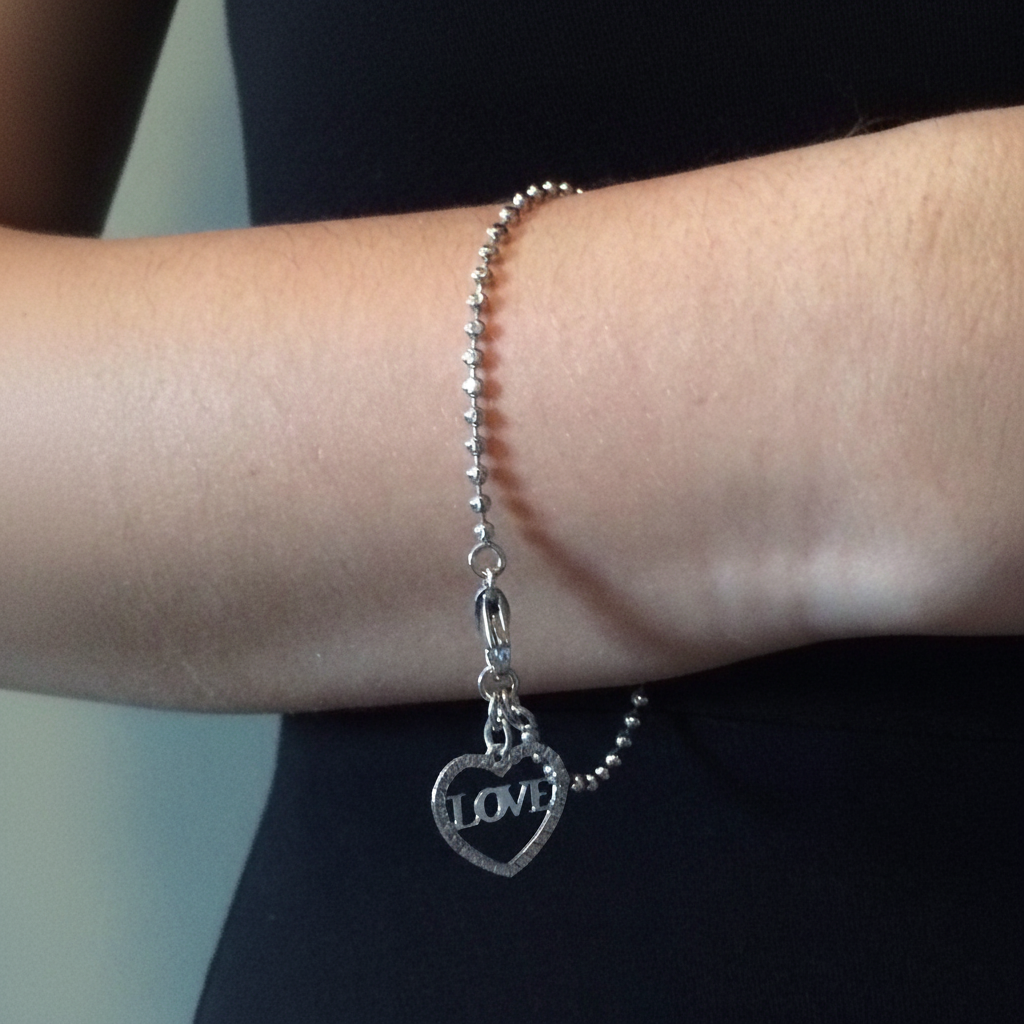 Sterling Silver Heart LOVE Charm Bracelet On A Womans Wrist.