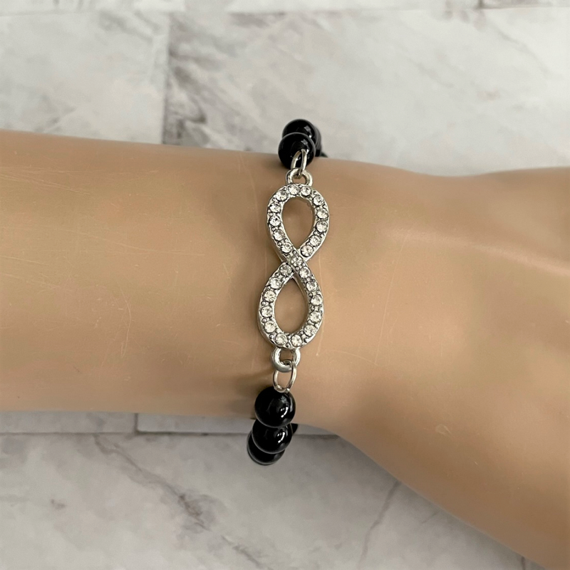 A bracelet with black onyx beads and a silver crystal infinity charm, with a sterling silver lobster clasp.