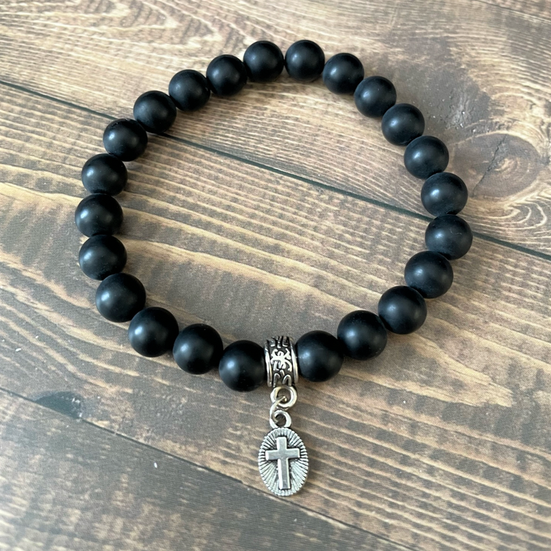 Men's bracelet with matte black onyx beads and a silver oval cross charm.
